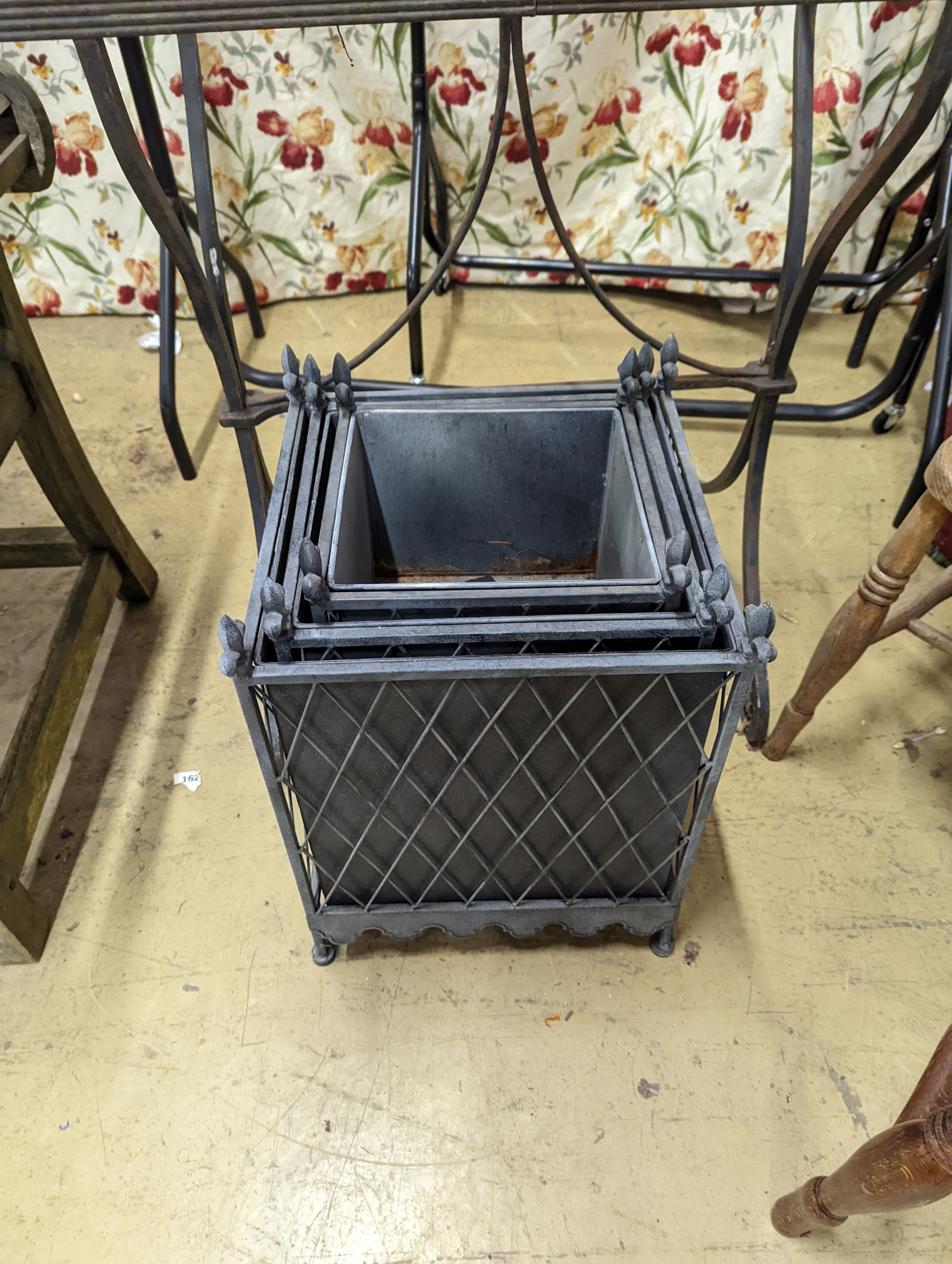 A Victorian style wrought iron pot stand, width 110cm, height 95cm, together with a graduated set of three square metal planters